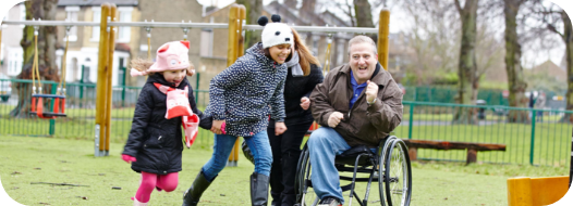 disabled man in wheelchair with his family playing in a park